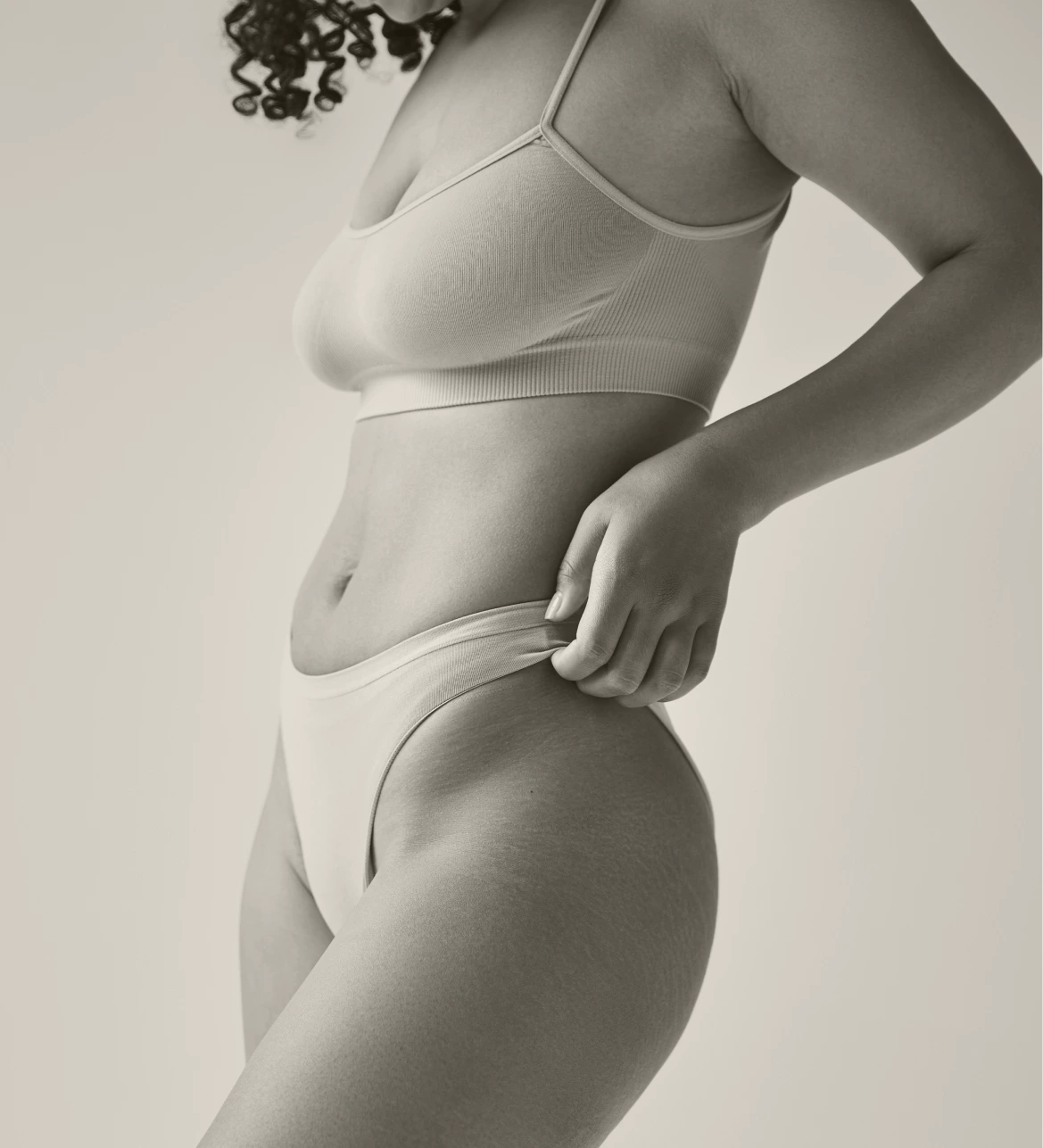 Woman in profile wearing white undergarments, demonstrating body contouring results